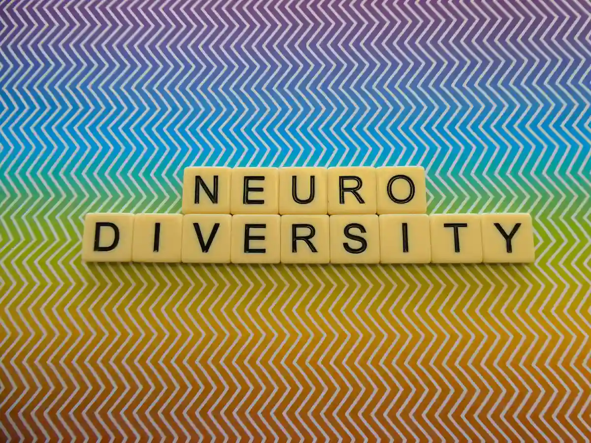 Tiles that spell neurodiversity on a background that is rainbow in color